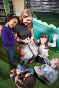Teacher in school library with class of young children, learning with flashcards